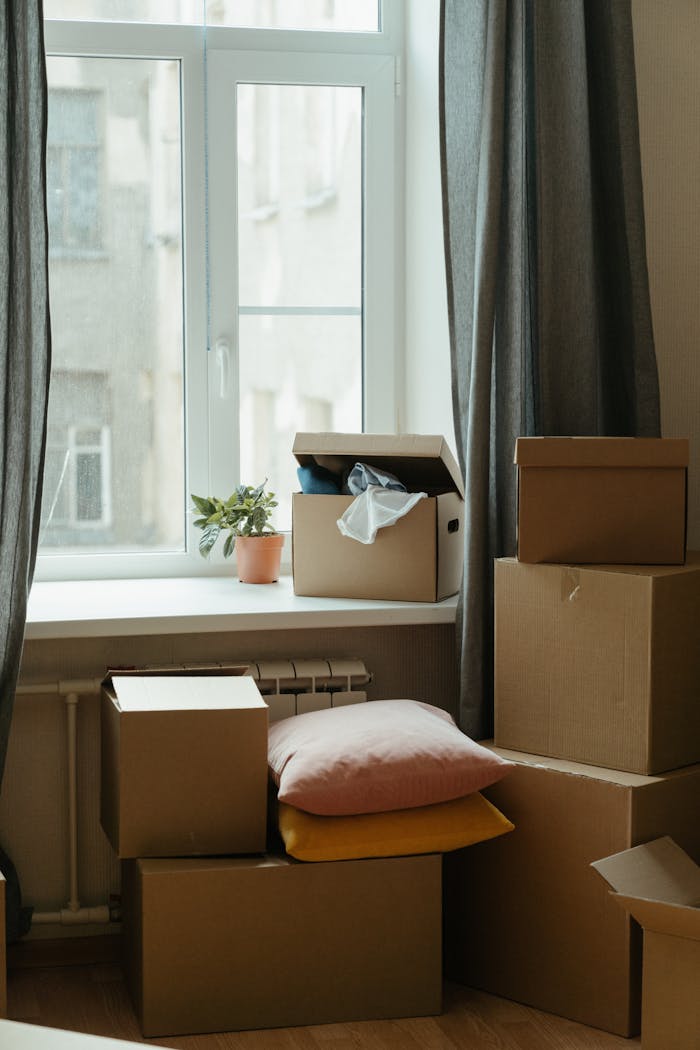 services-01 Stack of moving boxes in a sunlit room, symbolizing a fresh start in a new apartment.